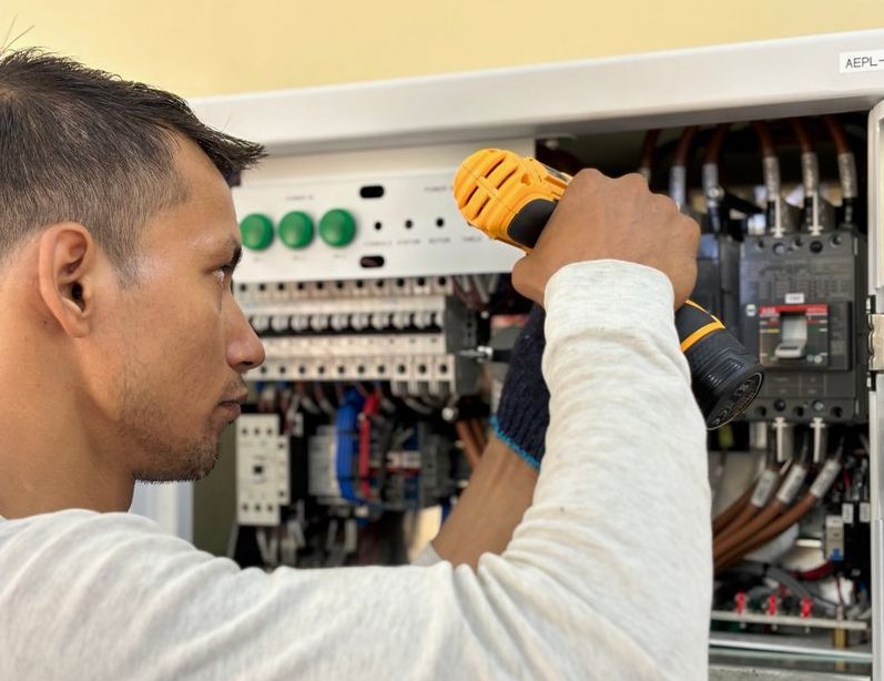 Professional electrician using a drill on an indoor circuit breaker panel
