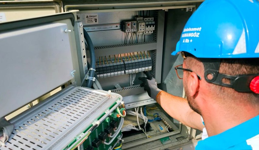 An electrician works on an outdoor fusebox, ensuring safety and functionality