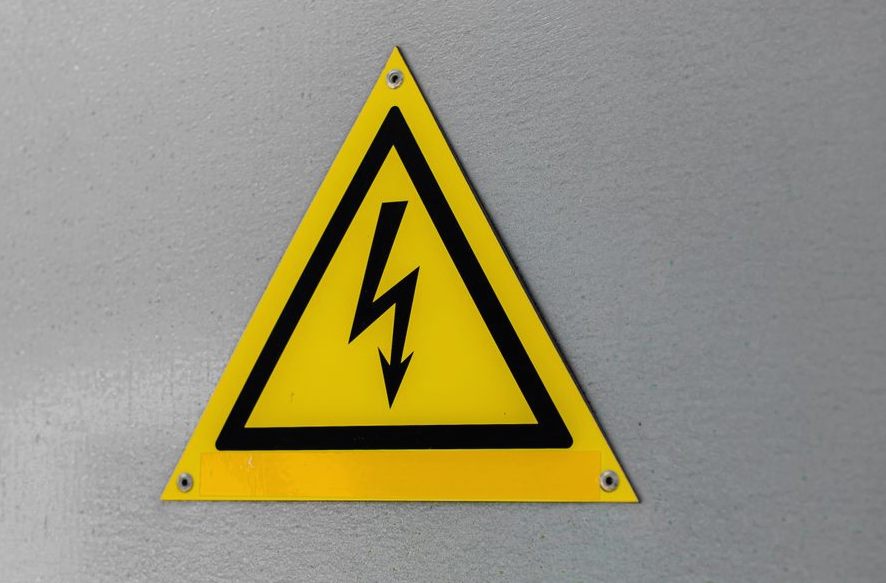 Close-up of a yellow high voltage warning sign mounted on a wall